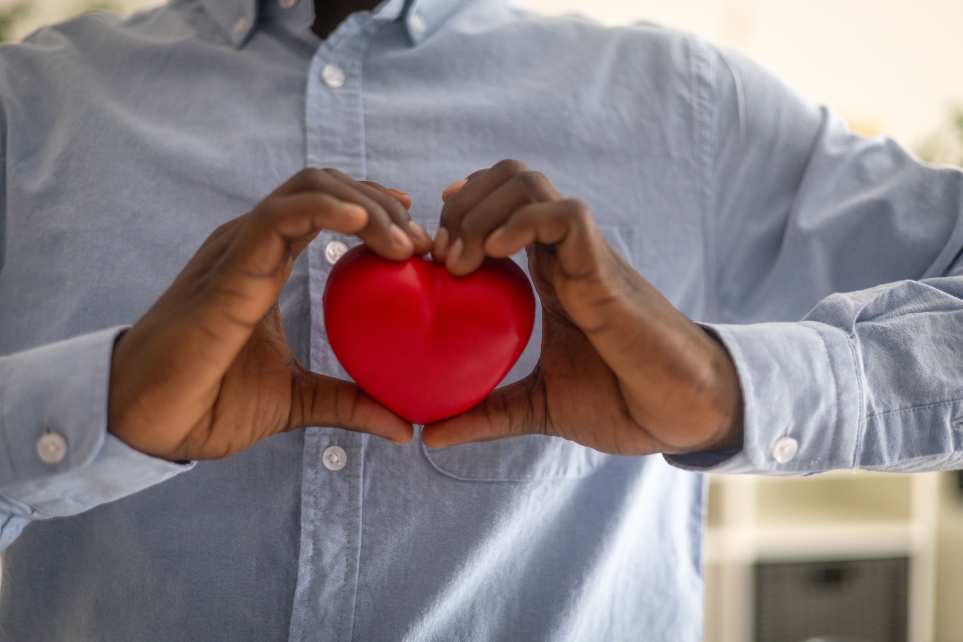 Businessman showing red heart with hands, representing health, charity, and love